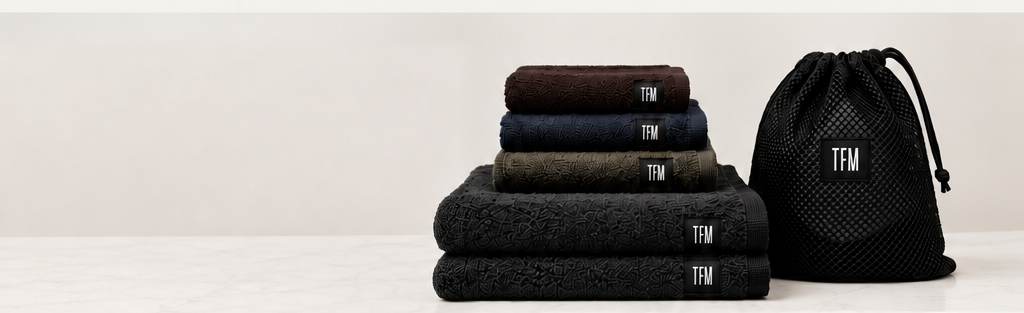 Stack of folded TFM towels with mesh bag on a marble surface